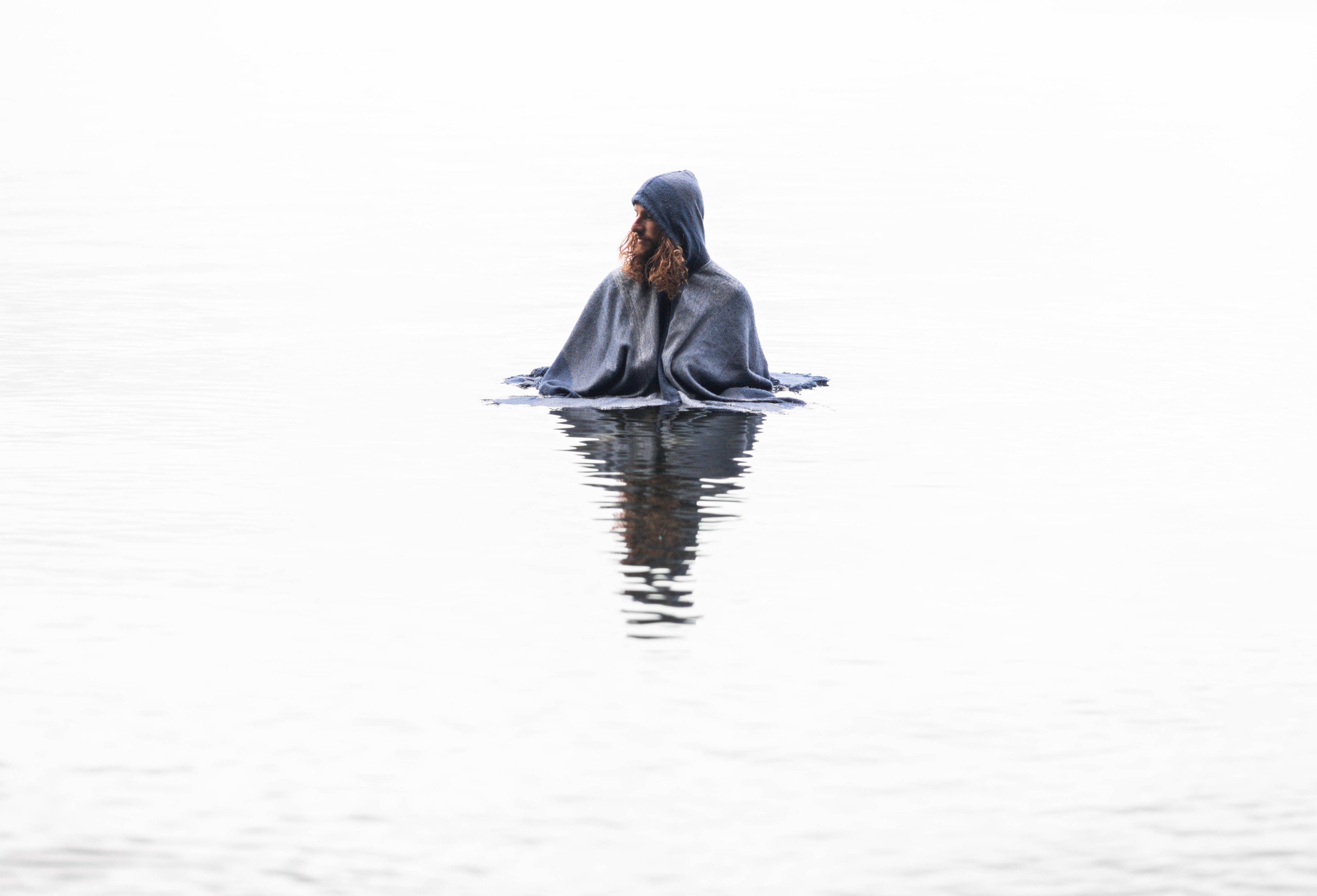 Hooded figure in still water